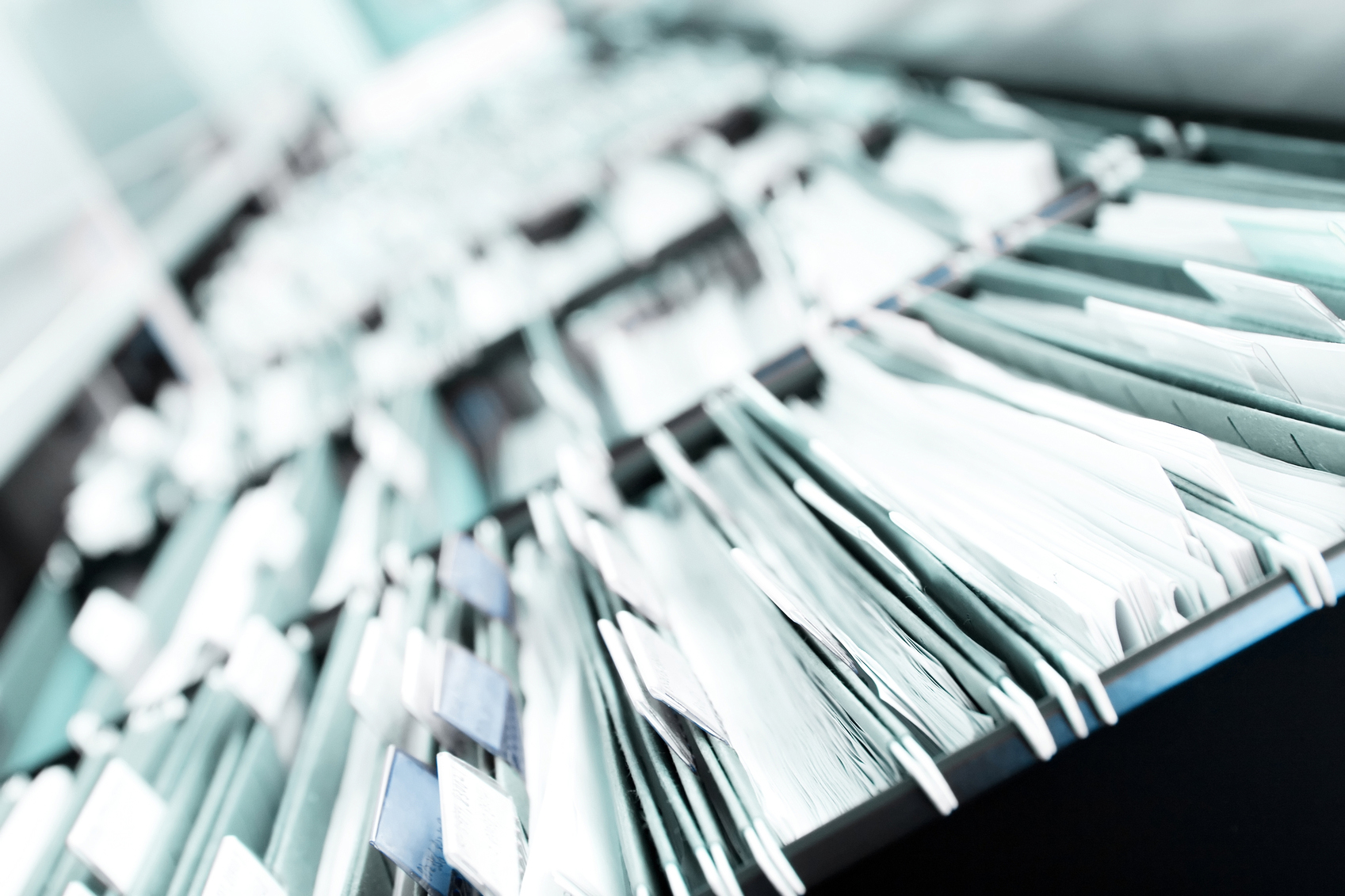 Multiple rows of filing cabinets in an office or medical establishment, overflowing with files.  Narrow depth of field to emphasize the "neverending" feeling